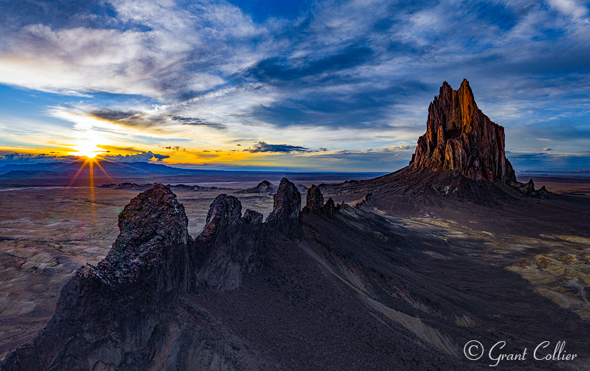 The sun sets behind Shiprock in New Mexico, as seen from an aerial perspective.
